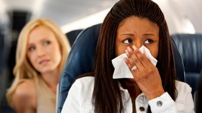 Woman blowing her nose on airplane