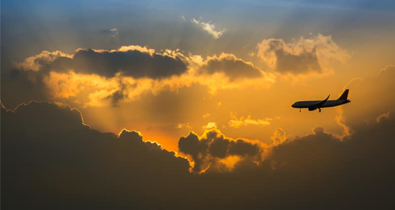 Plane flying in clouds during sunset