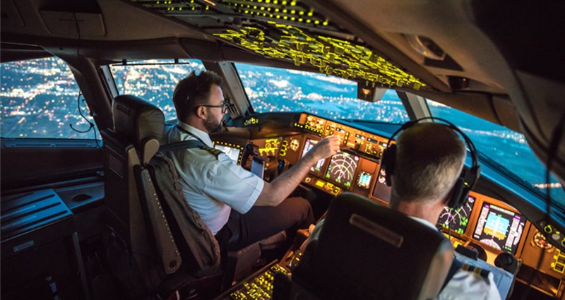 Two pilots in cockpit flying above a city