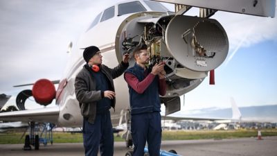 Two technicians working on front of plane