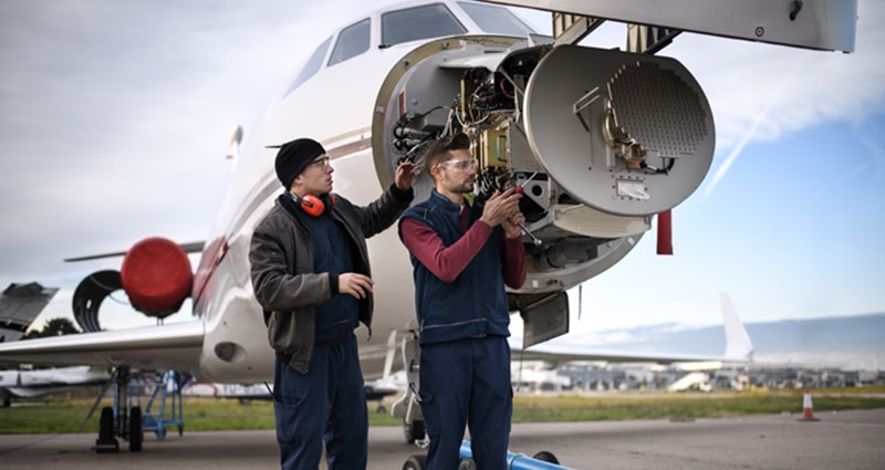 Two technicians working on front of plane