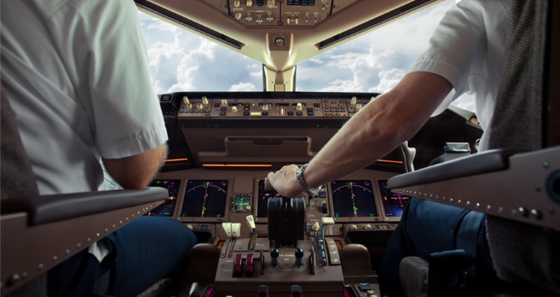 Close up of 2 pilots in cockpit flying airplane