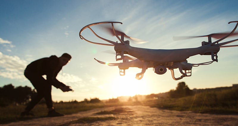 Man flying drone at sunset