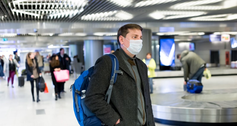 Man wearing face mask waiting for luggage