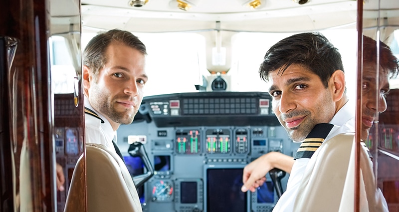 Two pilots smiling from the cockpit