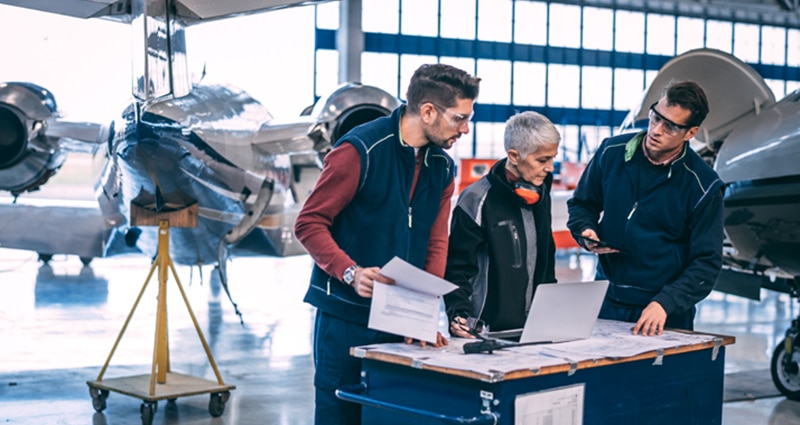 Technicians studying blueprints in hangar