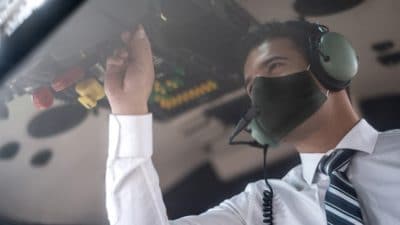 Pilot wearing face mask completing preflight checklist
