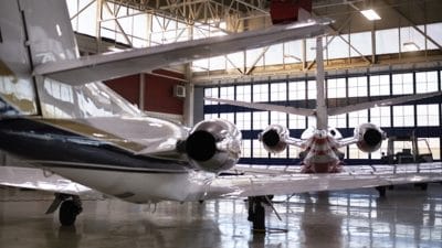 Two parked airplanes glistening in a well-lit hangar