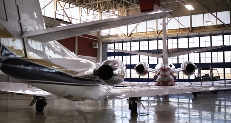 Two parked airplanes glistening in a well-lit hangar