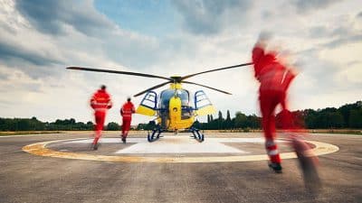 Air rescue service team running to the helicopter on the heliport