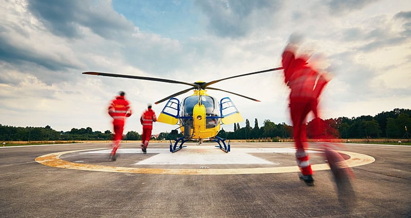 Air rescue service team running to the helicopter on the heliport