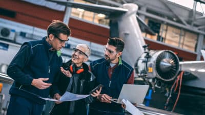 Aircraft crew coordinating in an aircraft hangar.