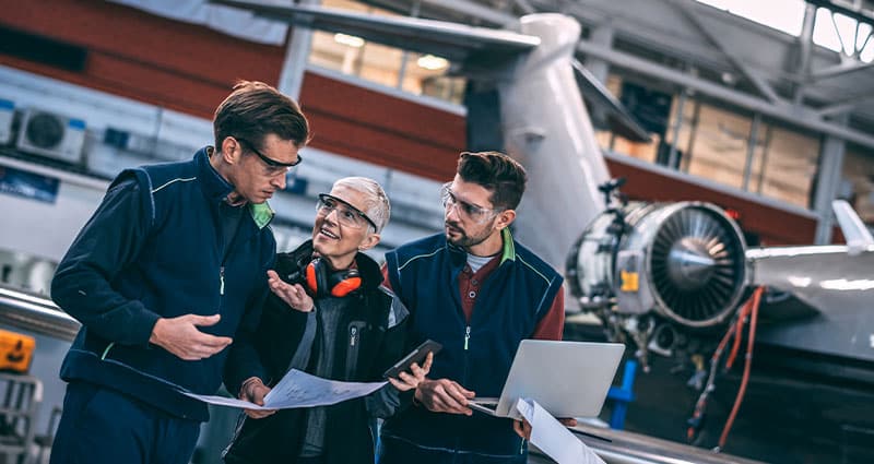 Aircraft crew coordinating in an aircraft hangar.