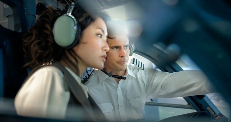 Pilot explaining how a flight simulator works to a student during a training session.