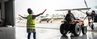 Woman signaling the pilot with marshalling wands at airport