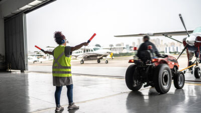 Woman signaling the pilot with marshalling wands at airport