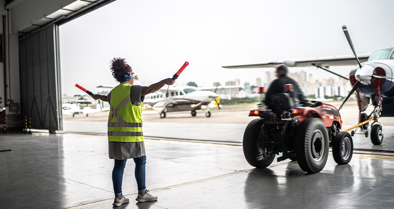 Woman signaling the pilot with marshalling wands at airport