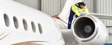 Aircraft mechanic inspects a jet in hangar at airport