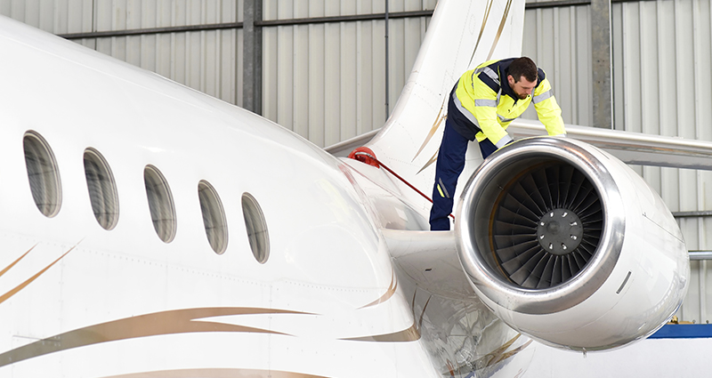 Aircraft mechanic inspects a jet in hangar at airport