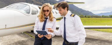 Pilots outside a private jet plane preparing flight path and check list from digital tablet