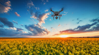 Flying drone over field in spring with dramatic sunset clouds